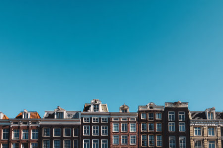 Colorful historic buildings stand tall along the waterfront in Amsterdam. The clear blue sky enhances the beauty of these architectural gems, attracting many visitors daily..の素材