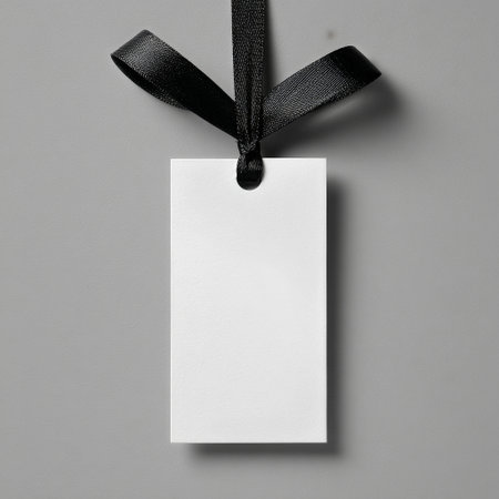 A simple, empty white tag hangs from a black ribbon against a gray background, highlighting clean lines and minimalist style, suitable for branding or crafting projects.の素材
