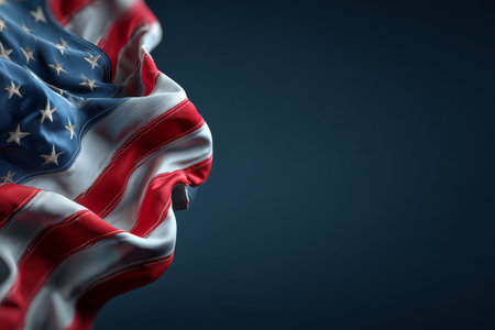 An American flag showing its stars and stripes waves gently against a dark background, emphasizing the intricate fabric and colors, creating a striking visual effect.. Details matter.の素材