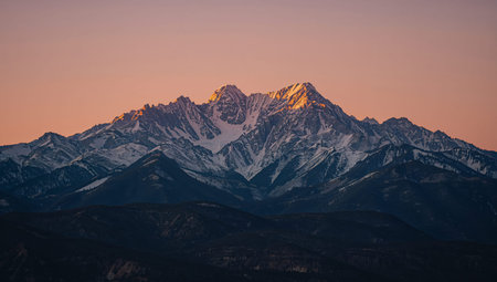 Snow blankets the mountain tops as the sun rises, casting soft light across the snowy landscape and rocky slopes. Nature shows its beauty at this early hour in the mountains.の素材