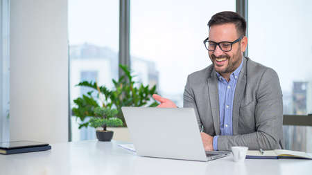 Attractive young caucasian manager with a stylish short beard talking online with his team...