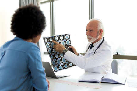 Serious Caucasian male doctor in white medical uniform talk discuss results or symptoms with female...