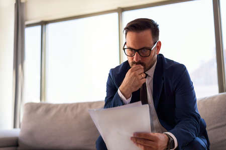 Young successful manger looking at the paper reading latest stock reports thinking about next investment planの写真素材