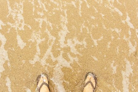 on a sunny day sea wave washes sand and legsの写真素材