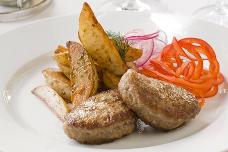 Grilled beefsteak with fries and onion rings and pepper on a white plate