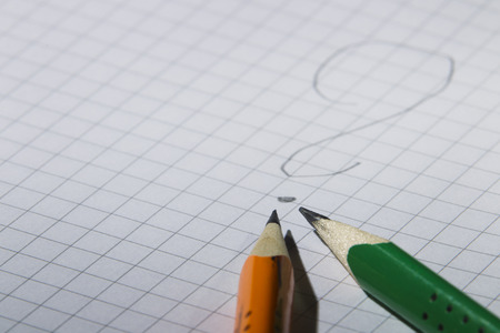 Two pencil, orange and green on a background of notebook sheet in the box, studio light illumination pointの写真素材
