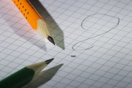 Two pencil, orange and green on a background of notebook sheet in the box, studio light illumination...