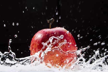 Red apple with splashes and drops of water on black and white background, studio lighting, Macroの写真素材
