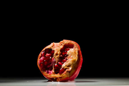 Pomegranate with drops and splashes water on black and white background, studio lightingの写真素材