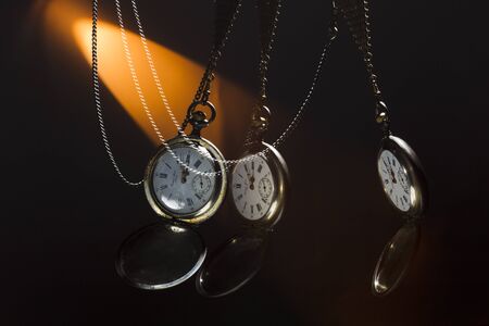 Antique silver pocket watch on a chain, spot colored studio light