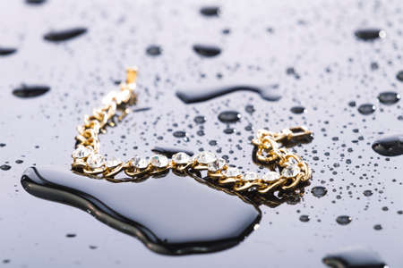 Gold bracelet with stones and water drops on light plastic background, studio lighting, Macroの写真素材