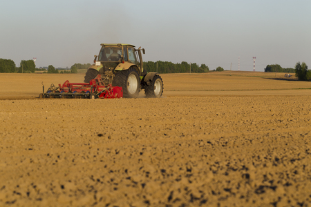 Tractor during agricultural work in the spring sunny dayの写真素材
