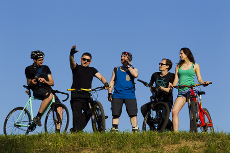 A group of young people, a man and a girl riding a bicycle in the city, lit by sunlightの写真素材