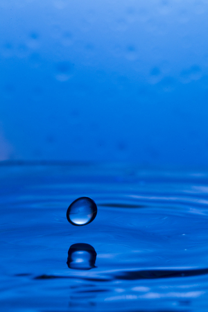 Bursts, spray, falling water droplets on a blue background, studio lighting, Macro