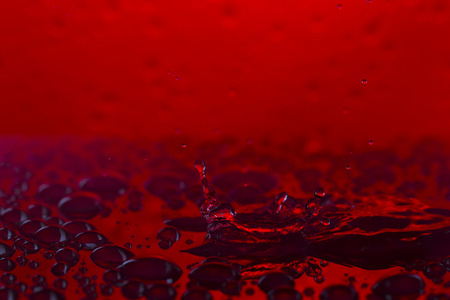 Bursts, spray, falling water droplets on a red acrylic background, studio lighting, Macroの写真素材