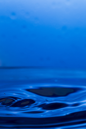 Bursts, spray, falling water droplets on a blue background, studio lighting, Macroの写真素材