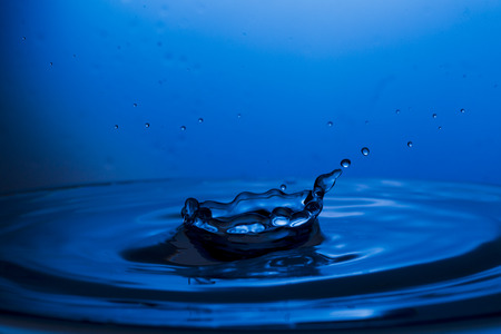 Bursts, spray, falling water droplets on a blue background, studio lighting, Macro