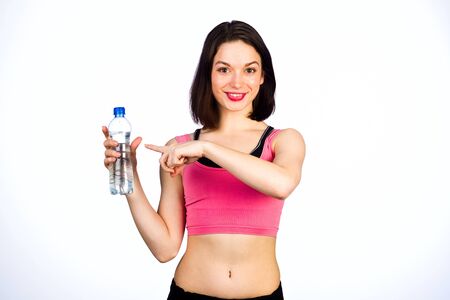 Young girl with a bottle of drinking water on a white background, studio lighting