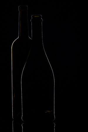 Red wine in wine glasses and wine bottle on a black background, silhouette, minimalism, studio lightingの写真素材