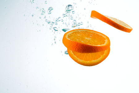 Orange in streams of water on a white background, studio lightの写真素材