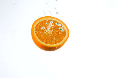 Orange in streams of water on a white background, studio lightの写真素材