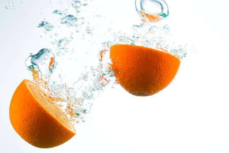 Orange in streams of water on a white background, studio lightの写真素材