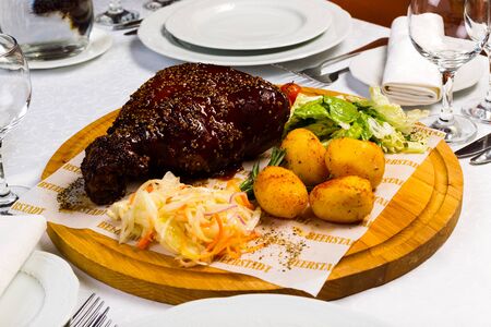 Grilled meat with garnish of vegetables on a wooden round board, studio lightの写真素材