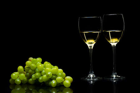 Grapes and three glasses for wine on a black background, studio lightの写真素材