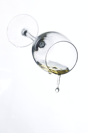 Drops of spray streams of wine and a glass on a white backgroundの写真素材