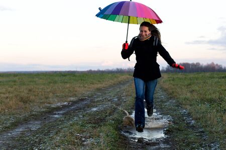 Young emotional woman with an umbrella on a walkの写真素材
