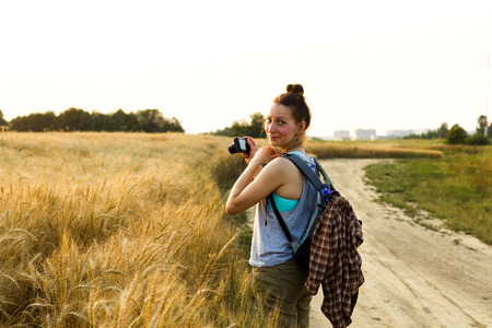 Young girl looks at the sunset on a summer evening at the edge of a rye fieldの写真素材