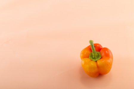 Sweet bellpepper. Yellow-orange sweet bellpepper on a beige background. One. Studio light. Top viewの写真素材