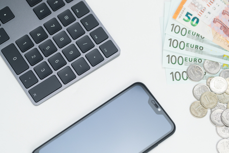 Finance. Money. Euro. Rubles. Dollar bills, smartphone and keyboard on a white background. Top view. Studio lightの写真素材