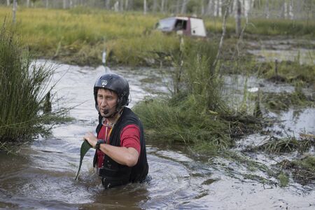 A man navigator of an SUV unwinds a tow rope to evacuate his SUV, off-road sport
