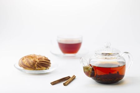 Transparent teapot with tea, glass cup and cake on white backgroundの写真素材