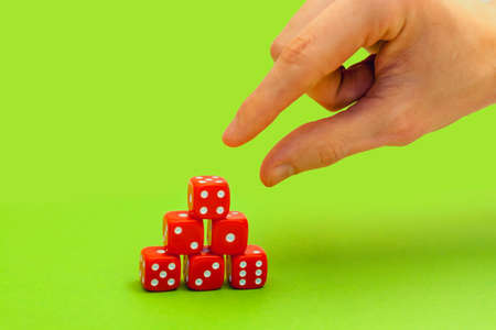 hand reaches red dice in a pyramid on green backgroundの写真素材