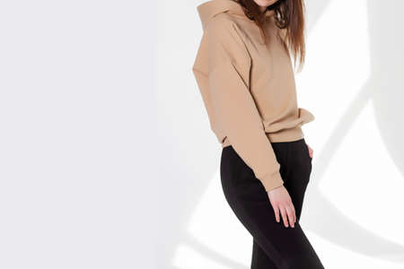 Young girl wearing blank sweatshirt and and sport pants. Gray wall background shadow light from the...