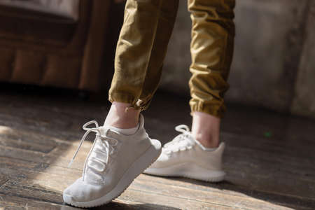Close-up of a woman's sneakers shoes walking on a live room backgroundの写真素材