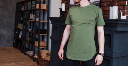 Casual man in khaki blank t-shirt. Standing in live room shirt for you mockupの写真素材