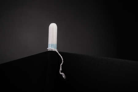 Tampon on dark table background. Female daily Intimate hygiene. Menstruation products for women...