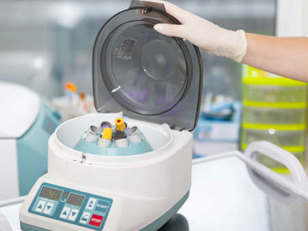 Medical centrifuge. Scientist loading a sample to centrifuge machine in the medical or scientific laboratoryの写真素材