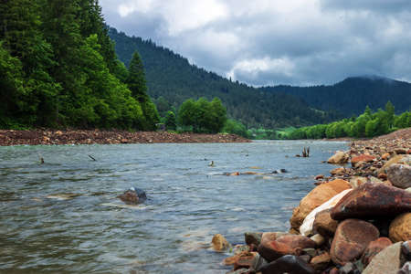 Clear river with rocks leads towards mountains lit by sunset