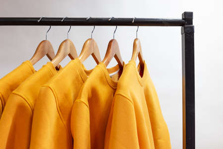 Blank sweatshirts hanging on a hanger in the wardrobe or showroomの写真素材