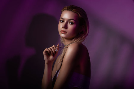 High fashion model woman face in colorful bright neon purple lights. Beautiful woman posing in the...
