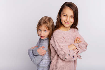 Best friends or sisters happy together stands closely each other resting hand on her friends shoulder. Smiling girls wear knitted sweaters leans at shoulder of friendの写真素材