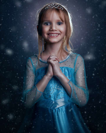 Young girl snow princess. Mystery fantasy girl in blue lush dress. Art background winter frozen and snow.の写真素材