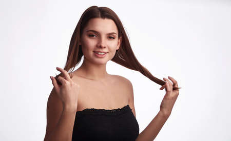 Pretty young fitness woman with straight hair in black sleeveless top sportswear on white...