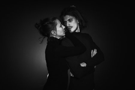 Love story concept. Portrait of a beautiful couple in love posing at studio over dark background....