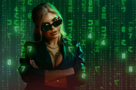 Gorgeous woman in matrix style suit. Black leather and reflection of code in glasses in green light...
