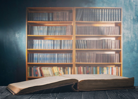 An open thick book on a wooden table and a bookcaseの写真素材